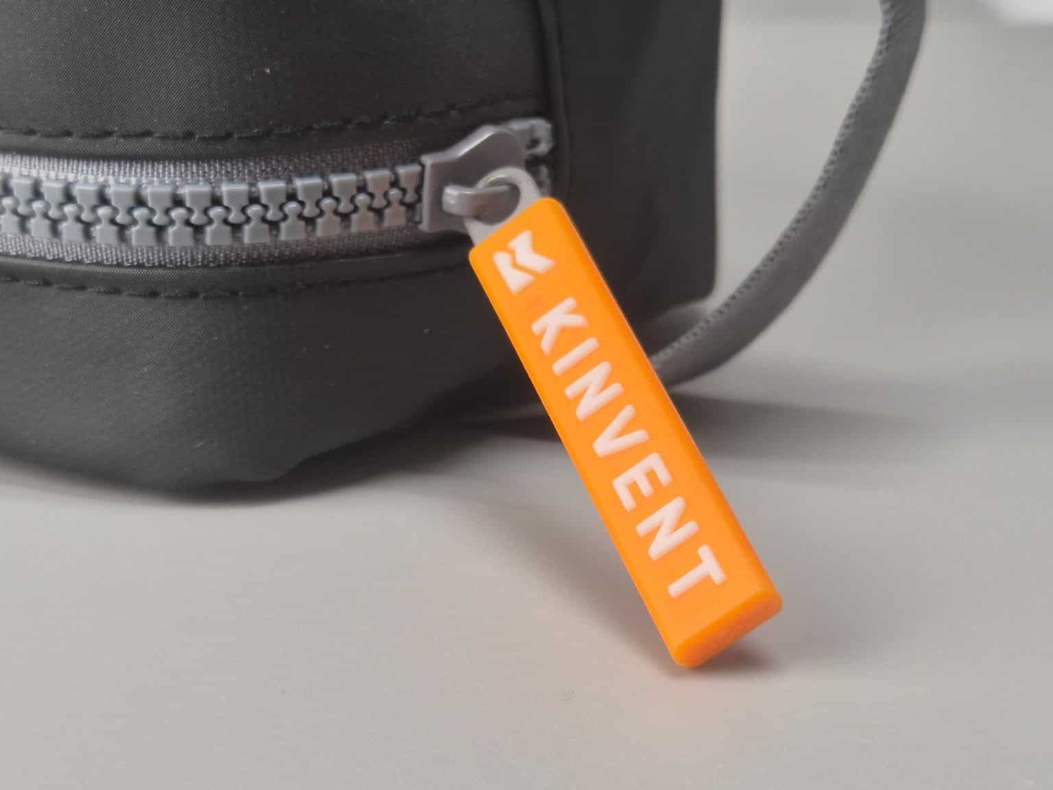 A compact TPU pouch with a zipper closure and a horizontal strap, featuring a silicone zipper puller and a rubber-printed K-Invent logo